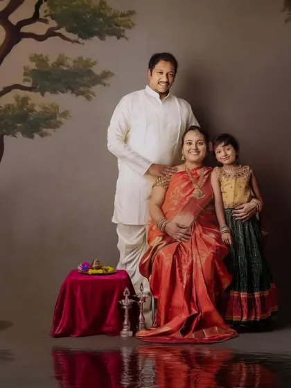 A regal family maternity portrait. The expecting mother is seated like royalty, surrounded by her family in a beautifully painted, traditional Indian setting.