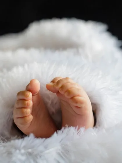 Sometimes it's the smallest details that hold the most love. This is a close-up shot of a newborn's tiny feet peeking out from a soft, fluffy white blanket. A simple, sweet memory from their first few days.
