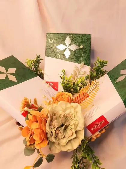 For this trousseau, I used elegant green and white boxes to package sweets. The simple floral arrangement adds a touch of freshness, making it a sophisticated gift for any wedding-related event.