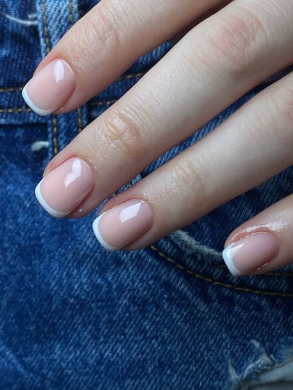 A classic French manicure on short, natural nails against a denim background. This timeless look is versatile and effortlessly chic for everyday wear.