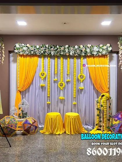 This beautiful indoor Haldi setup features traditional marigold garlands, hanging floral elements, and a personalized welcome sign to greet your guests.