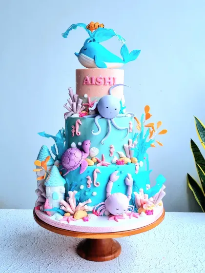 An imaginative four-tier underwater fantasy cake, perfect for a big celebration. The design features a variety of sea creatures like a friendly whale, octopus, and turtle, all handcrafted from fondant and set against a beautiful ocean-colored cake, creating a vibrant deep-sea adventure.