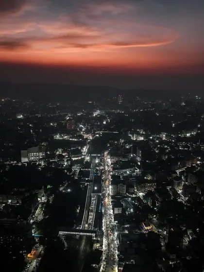 A wide aerial view of Badlapur at night, showing the main artery of the city lit up.