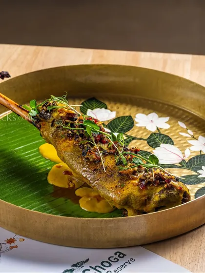 A beautifully plated roasted chicken leg for Dana Choga Reserve. The elegant brass plate and banana leaf add a touch of luxury.