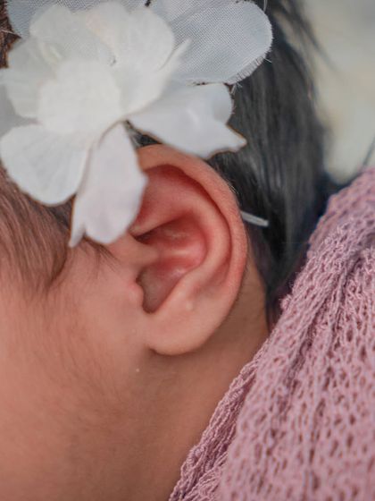 A macro shot focusing on the delicate details of a newborn's ear and the flower in her hair. These tiny features change so quickly, making these shots priceless.