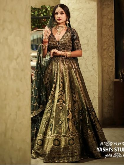 A full-length portrait of a model in a stunning olive green and gold bridal lehenga.