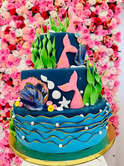 Dive into a magical celebration with this multi-tiered mermaid theme cake. It’s decorated with handcrafted fondant seaweed, shells, and mermaid tails, creating an enchanting underwater scene perfect for a fantasy-themed birthday.