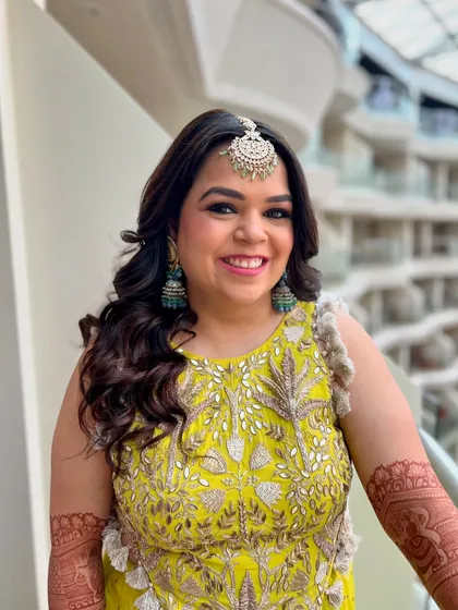 For this vibrant Mehendi look, I styled the hair in open, bouncy curls. This fun and festive hairstyle is perfect for a daytime event and complements the client's cheerful yellow outfit.