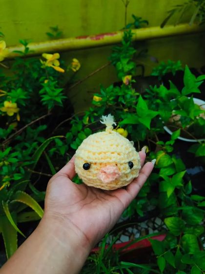 Here is the little crochet chick held against a green, leafy background. The yellow really pops. I can add a keyring to this to make it a custom charm.