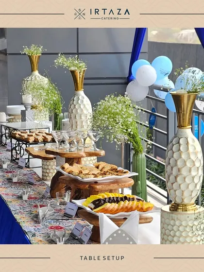 A bright and airy table setup for a daytime event. The white and gold vases filled with baby's breath and the light wood risers create a fresh and elegant look.