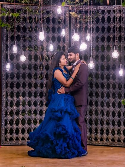 The hanging bulbs in front of the large gate provide a dramatic and stylish backdrop for a modern couple's photoshoot.