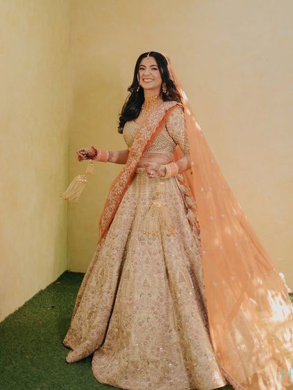 A full-length shot of the bride, her smile radiant and her peach dupatta flowing beautifully in the breeze.