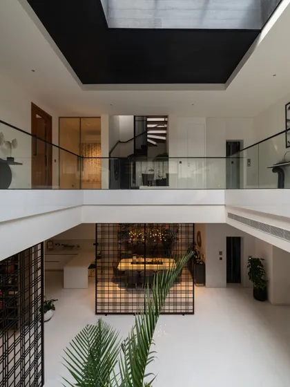 The interior of Residence 100 features a dramatic double-height space with a central courtyard view, promoting openness and vertical connectivity between floors.