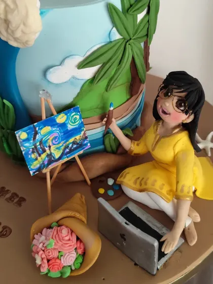 A close-up of the figurine on the "workaholic wife" cake, showing her painting "Starry Night" with her laptop by her side.