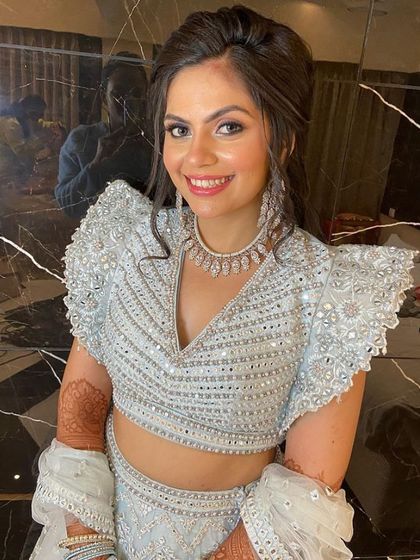 A close-up of our smiling client in the powder blue lehenga, showing the detailed neckline and matching diamond jewelry.