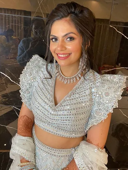 A close-up of our smiling client in the powder blue lehenga, showing the detailed neckline and matching diamond jewelry.