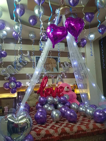 A romantic room decoration with a canopy, fairy lights, and purple and silver balloons. This setup can be used for birthdays, anniversaries, or even to say "Sorry".