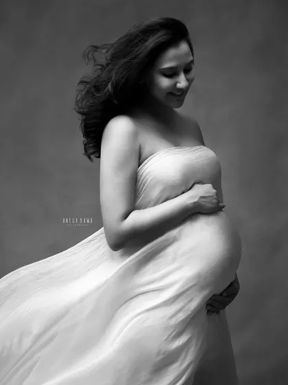 The beauty of movement. This black and white image captures a flowing fabric as it wraps around the mother-to-be, creating a sense of motion and ethereal grace.
