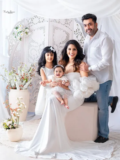 A joyful family photo where everyone is smiling. The coordinated white outfits and bright studio lighting result in a perfect family portrait.