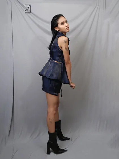A profile view that highlights the peplum detail of the top and the model's confident stance.