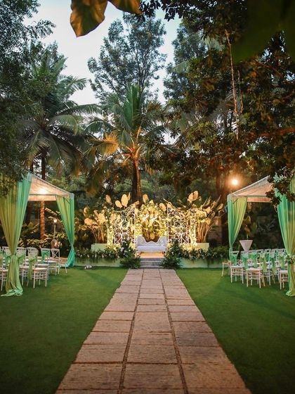 The main lawn at Farmhouse Collective set for an evening reception. The stage is lit, and the green drapes add a pop of color to the elegant setup.