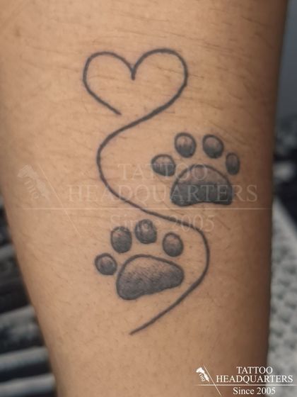 A tattoo for dog lovers, this design features two paw prints connected by a single line that forms a heart.