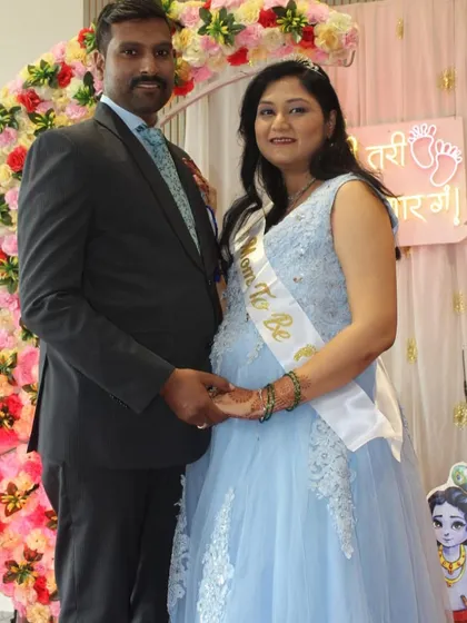 A beautiful moment from a baby shower celebration. The mom-to-be shines in a powder blue ball gown with delicate white embroidery, holding hands with her partner.