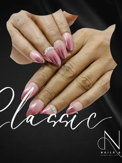 A beautiful pink chrome ombre on stiletto nails. This design is accented with a delicate band of rhinestones at the cuticle for a touch of classic glamour.