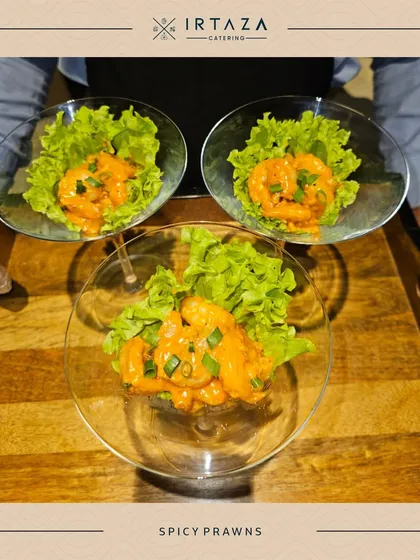 Spicy Prawns served elegantly in martini glasses on a bed of crisp lettuce. This is a sophisticated and visually appealing way to serve a seafood appetizer at a high-end event.