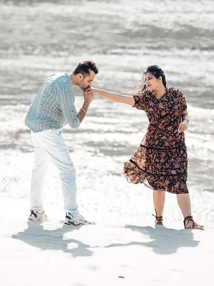 A classic romantic gesture, with him kissing her hand on the sparkling riverbank. The backlighting from the sun on the water adds a magical touch.