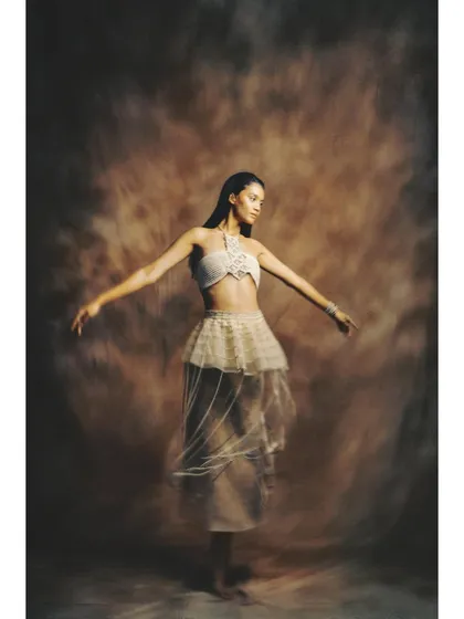 A shot from 'Sandcastles' that captures the movement of the sheer, layered skirt. The painterly backdrop and soft lighting enhance the dreamy, transient theme of the editorial.
