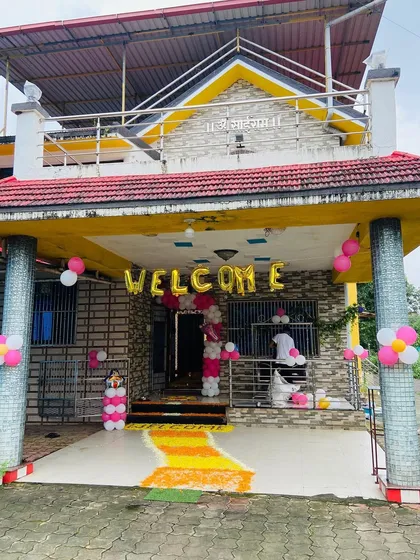 The exterior of a house decorated with 'WELCOME' foil balloons and pink balloon clusters to announce the baby girl's arrival.