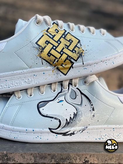 A close-up showing both the Karma symbol and the white wolf design on the same pair of custom Adidas sneakers.