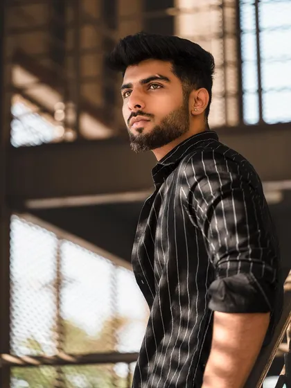 A portrait of a model in a pinstripe shirt against an industrial background. The contrast between the formal shirt and the setting creates a modern, edgy feel.