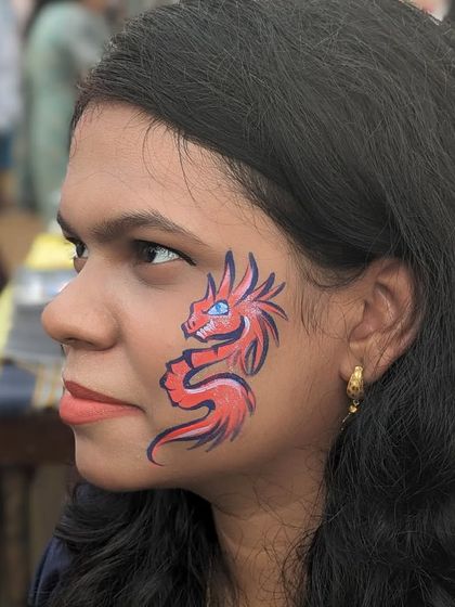 A small but mighty red dragon painted on a client's cheek.