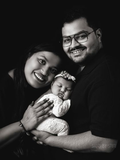 A happy family of three in a classic black and white portrait. Their smiles are infectious.