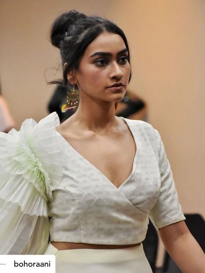 A backstage moment with a model wearing our signature ruffled sleeve blouse. This close-up highlights the texture of the fabric and the unique silhouette of the sleeve.