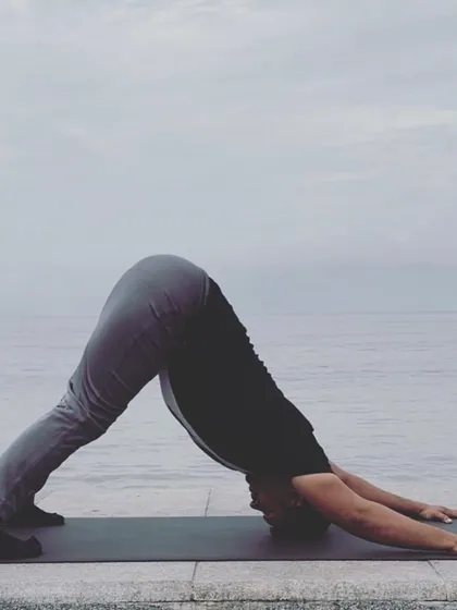 Adho Mukha Svanasana (Downward-Facing Dog) by the ocean. A foundational pose that stretches and strengthens the entire body.