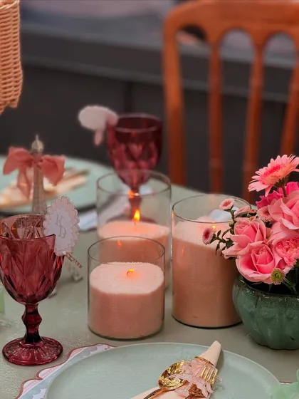 Soft candlelight adds a warm and intimate glow to the baby shower tablescape, highlighting the pink floral arrangements and elegant glassware.
