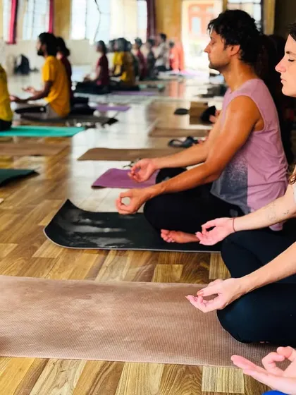 Two students, one from India and one from abroad, meditate side-by-side. Yoga is a universal language that connects us all.
