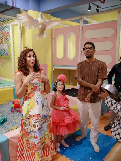 A family watches in awe as a magician performs a trick with a live dove at a unicorn-themed party. This is the kind of magical moment we specialize in creating.