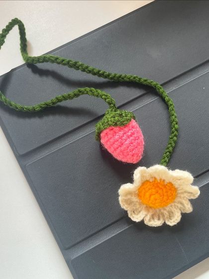 Another view of the daisy and strawberry bag charm, a sweet and whimsical accessory.
