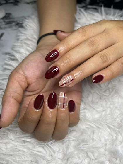 A deep red manicure with a nude and red plaid accent nail. This is a great example of a cozy, autumn-themed design.