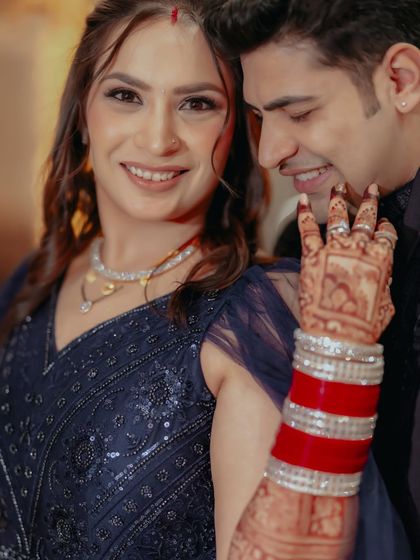 A post-wedding shot of Kritika and Lokesh, her bright red choora and intricate mehendi standing out against her deep blue saree.