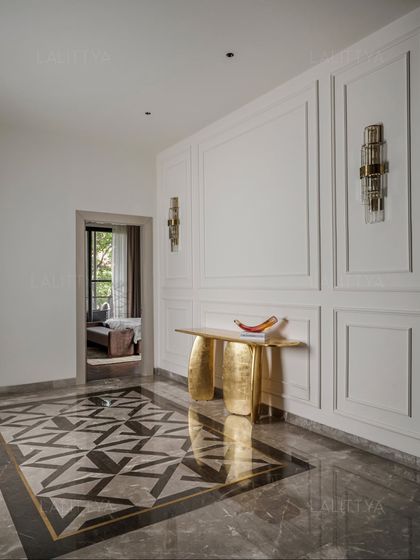 An entrance designed with restraint and clarity. The foyer features a stunning geometric marble inlay on the floor, a sculptural gold console table, and elegant wall sconces, reflecting the essence of minimal yet luxurious interiors.