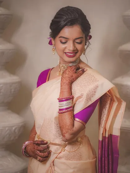 A beautiful portrait of the engagement bride. Her cream and purple saree, delicate jewelry, and happy expression are all captured in soft, flattering light.