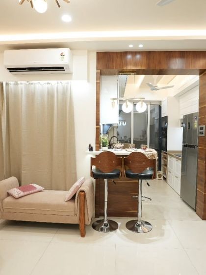 This view shows the living area and its connection to the open kitchen. The breakfast bar with high chairs serves as a casual dining spot and a social hub.