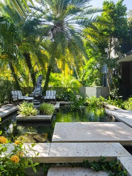 A modern koi pond integrated with concrete platforms and lush tropical planting. This design blends hardscape and softscape elements to create a tranquil and contemporary water garden.