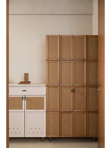 A closer look at the foyer's custom storage. The tall unit features cane laminate panels, while the shoe rack below has perforated details for ventilation, blending practicality with natural textures.