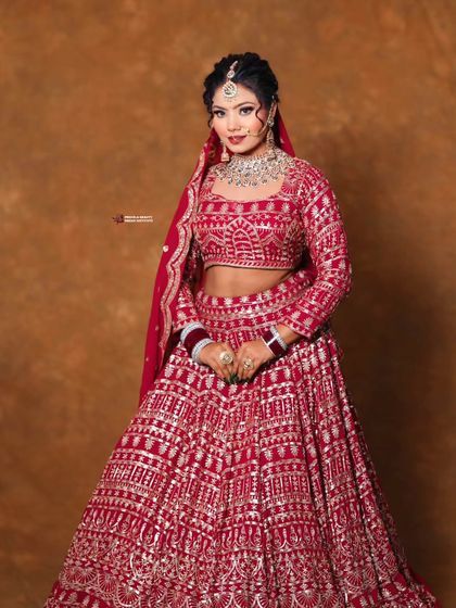 A modern bridal look with a touch of tradition. The soft updo complements the sparkling red lehenga and diamond jewelry for a fresh and glamorous wedding style.